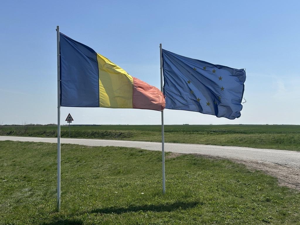 Rumänische und EU-Flagge an einer kleinen Landstraße am Grenzübergang.