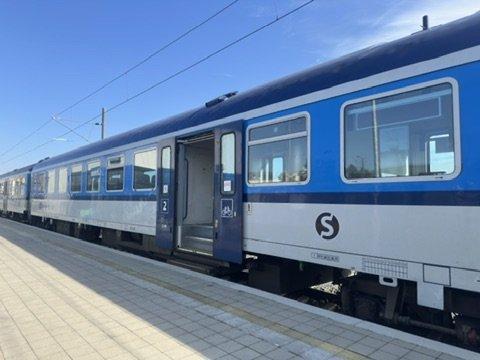 Blau-weißer Reisezugwagen am Bahnsteig.
